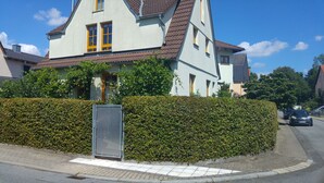 A two-story house with a tiled roof, a small garden, and a metal fence. - Modern Strata Montana vacation apartment with garden, underfloor heating and air conditioning (Bensheim)