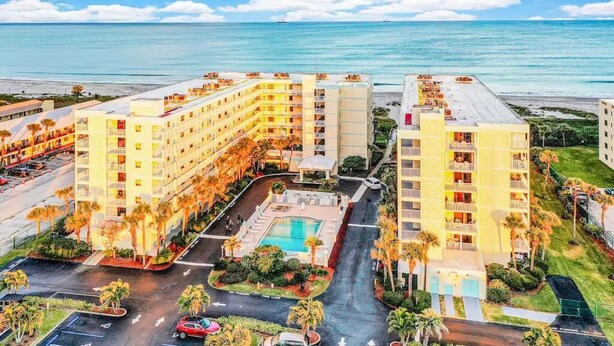 A hotel with multiple floors, a swimming pool, and a view of the ocean. - Sandcastles 2BR/2BA Cocoa Beach Ocean Views! Heated Pool! (Cocoa Beach)