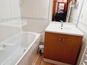 Un baño con bañera, lavamanos y espejo.
