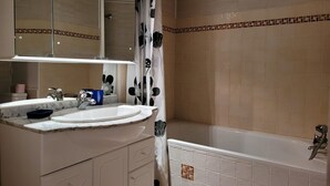 A bathroom with a sink, mirror, and bathtub. - Renovated studio for 4, south, near slopes and mall (Pra-Loup)