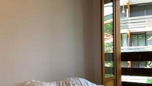 A bedroom with a bed, a window, and a view of a building outside.