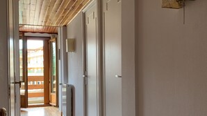 A hallway with wooden flooring, white walls, and a door leading to a balcony.