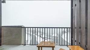 A balcony with a wooden table and two chairs, a metal railing, and a view of a snowy landscape. - 27m² Studio for 5 People with Balcony and Valley View (Saint-François-Longchamp)