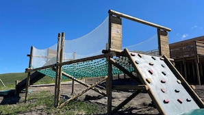 A wooden climbing structure with a netted enclosure, set against a clear blue sky. - 27m² Studio for 5 People with Balcony and Valley View (Saint-François-Longchamp)