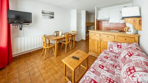 A compact living space with a dining area, kitchenette, and a TV mounted on the wall. - 27m² Studio for 5 People with Balcony and Valley View (Saint-François-Longchamp)