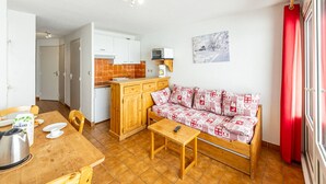 A compact living space with a kitchenette, a dining area, and a sofa. - 27m² Studio for 5 People with Balcony and Valley View (Saint-François-Longchamp)
