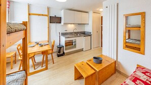 Una habitación pequeña con kitchenette, zona de comedor y cama.
