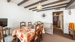 A dining area with a table set for six, wooden chairs, a sofa, a television, and a clock on the wall. - 8-person apt at the slopes, south-facing balcony, central location (Saint-François-Longchamp)