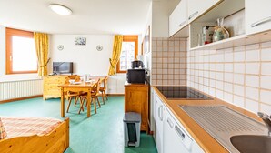 Une chambre d’hôtel compacte comprenant un coin cuisine, un espace repas et un lit.
