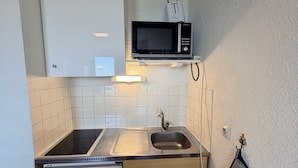 Une cuisine compacte équipée d’un four à micro-ondes, d’un évier et d’un petit réfrigérateur.