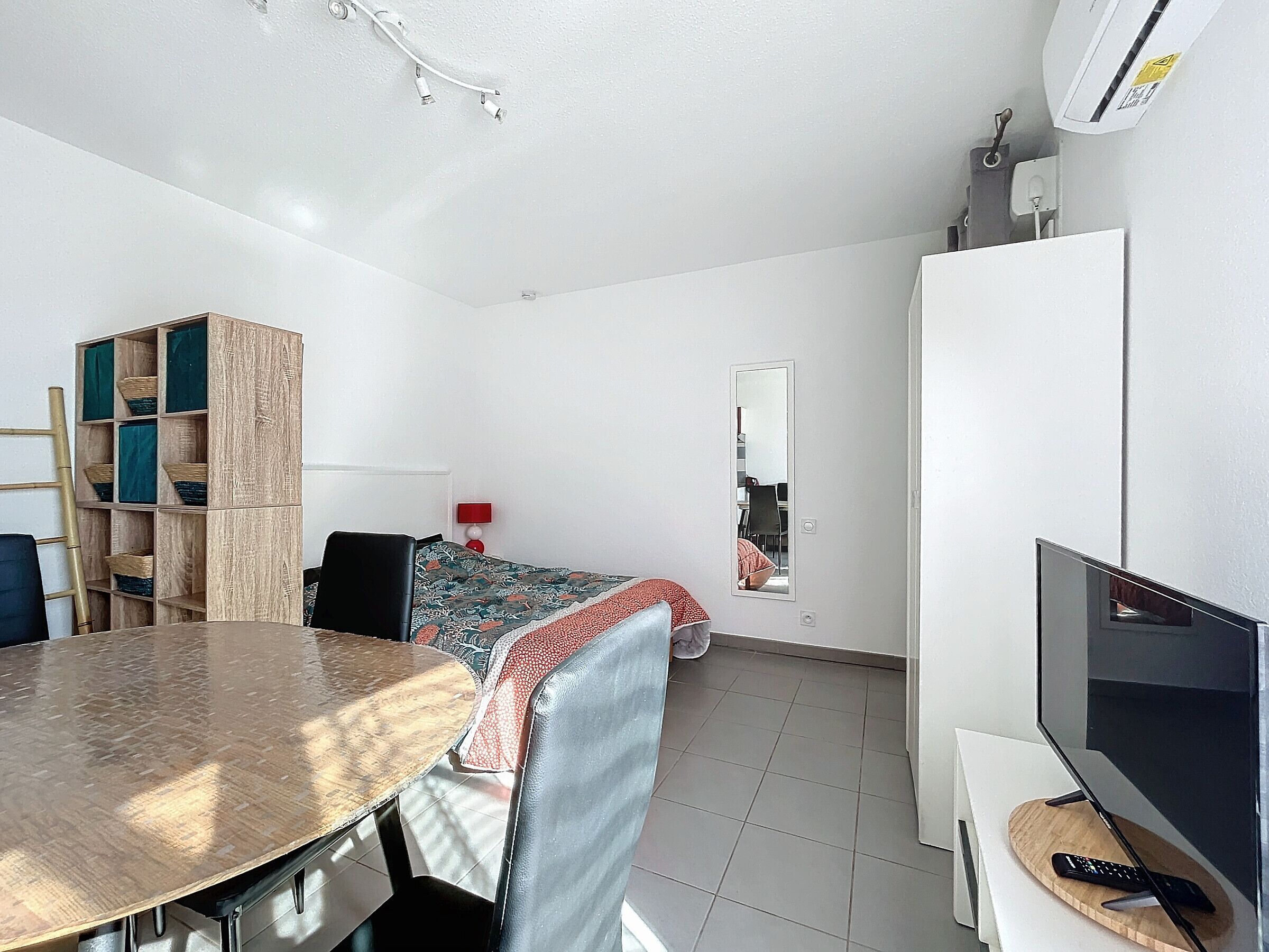 Una habitación pequeña con cama, escritorio, silla, televisor y armario.