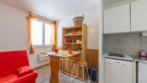 Eine kleine Küche mit einem Holztisch, Hockern und einem roten Sofa.