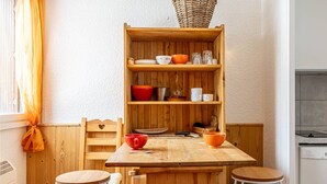 Eine kompakte Küche mit Holzschnitzerei, einer zentralen Kochinsel, zwei Barhocker und einem Fenster mit Vorhängen.