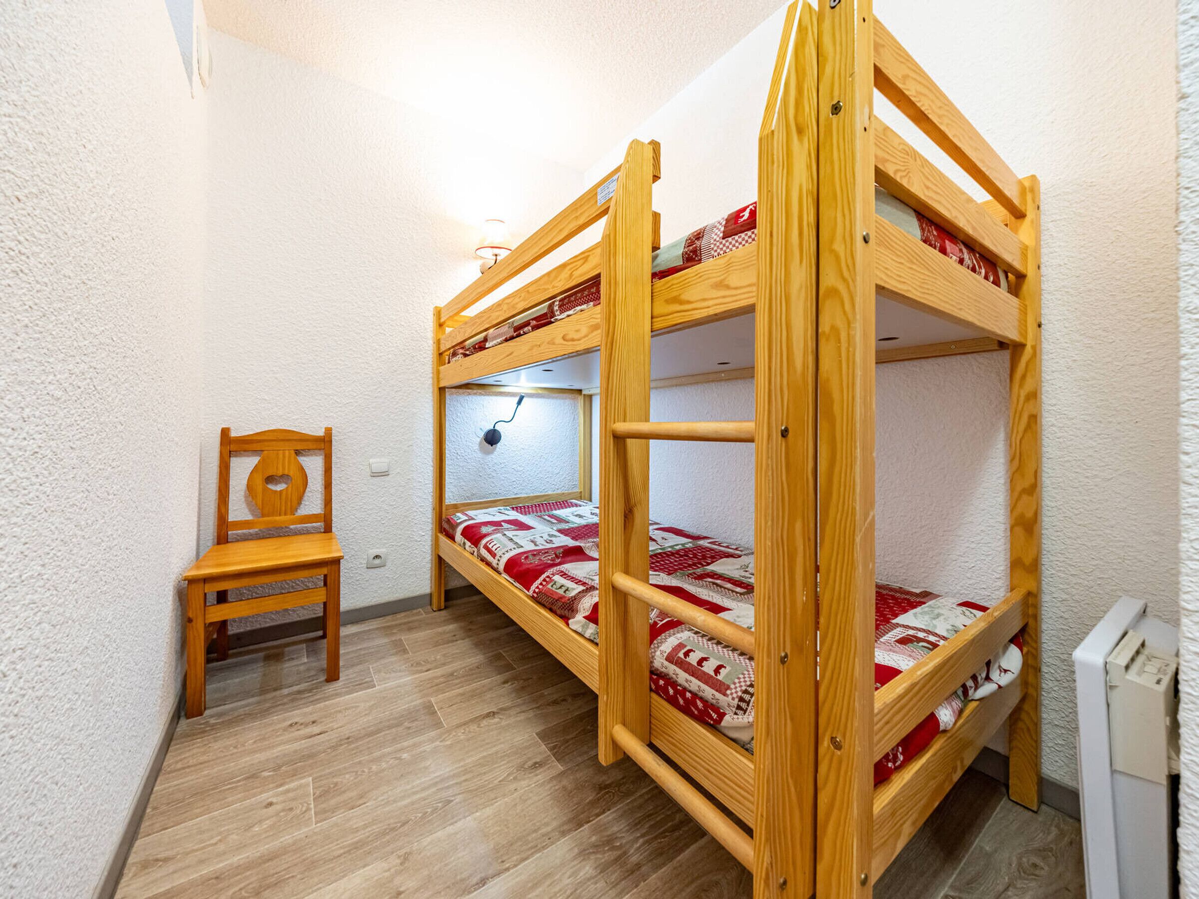 A bunk bed room with a wooden chair and a small desk.