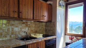 A kitchen with wooden cabinets, a tiled backsplash, a sink, a dishwasher, and a window with a mountain view. - 3 rooms for 6, south/east balcony near slopes (Pra-Loup)