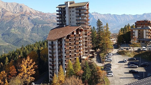 A multi-story hotel with balconies, surrounded by mountains and autumn foliage. - 3 rooms for 6, south/east balcony near slopes (Pra-Loup)