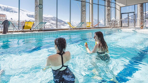 Una piscina interior con vistas claras a montañas nevadas a través de amplios ventanales.