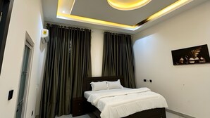 Camera da letto moderna con un letto, tende, un lampadario e un'opera d'arte appesa al muro.