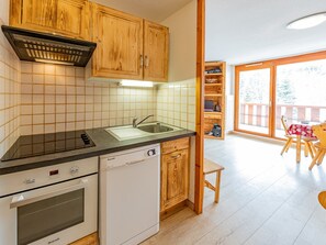 A compact kitchen with wooden cabinets, a dishwasher, and a built-in oven.