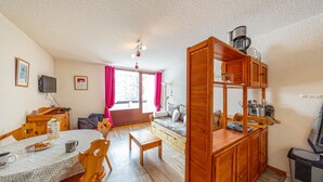 Una sala de estar acogedora con un sofá, una mesa de comedor con sillas, una cafetera y un televisor sobre un mueble.