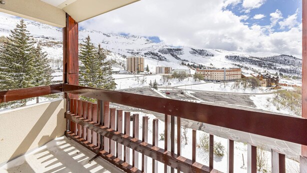 A balcony with a view of a snowy mountain landscape, buildings, and a clear sky.