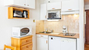 A compact kitchen with white cabinets, a microwave, a coffee maker, and a dishwasher.