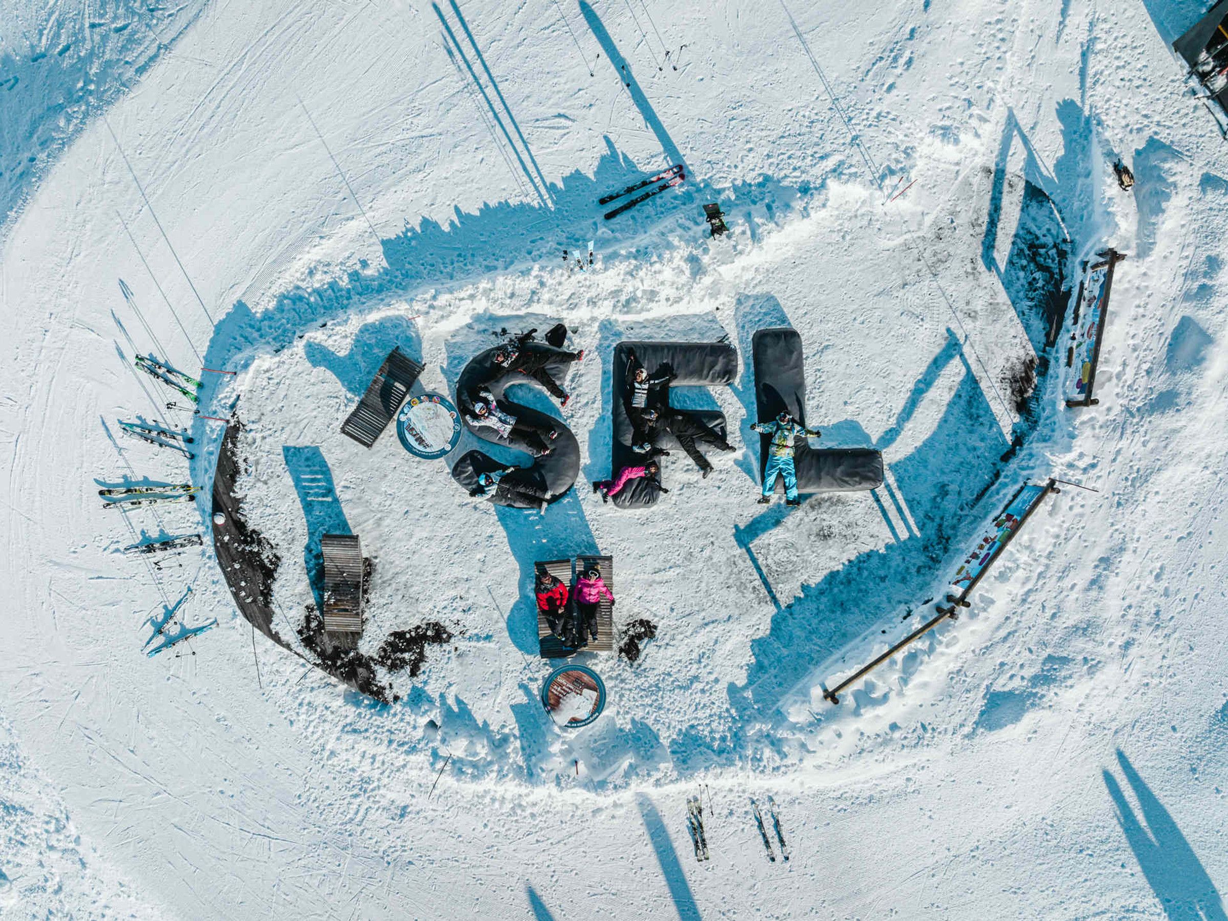 Luftaufnahme eines Skigebiets mit präparierten Skipisten und Aufzügen.