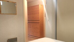 Makuuhuone, jossa on sänky, puinen vaatekaappi ja seinälle kiinnitetty peili.
