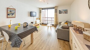 A modern, well-lit living area with a dining table, sofa, and TV. - Comfortable studio at the slopes for 4 people (Saint-François-Longchamp)