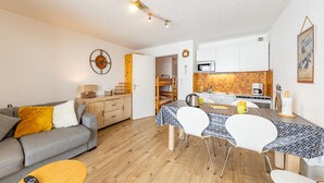A compact living space with a sofa, a dining table, and a kitchenette. - Comfortable studio at the slopes for 4 people (Saint-François-Longchamp)
