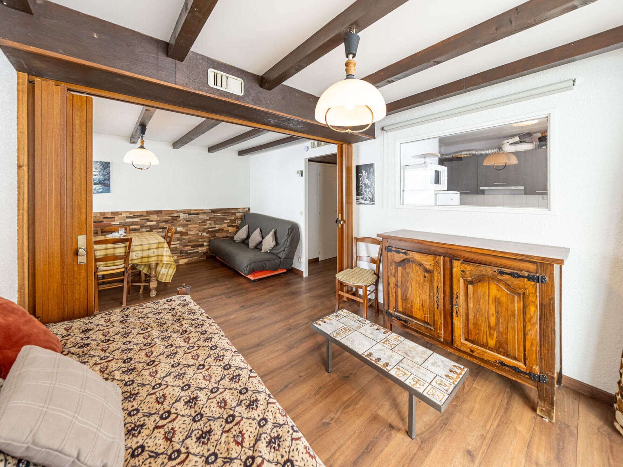 A cozy living room with a sofa, a wooden bench, and a dining area with a table and chairs.