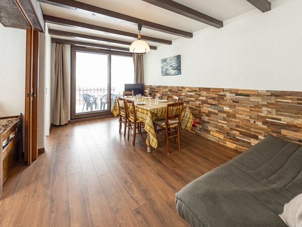 Ein Essbereich mit Holztisch, Stühlen und einem Fernseher.