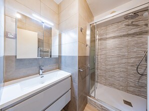A modern bathroom with a large mirror, a white sink, and a glass-enclosed shower. - Bright studio at the foot of slopes, near chairlift, balcony in Saint-François-Longchamp (Saint-François-Longchamp)