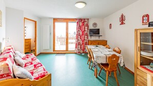 A cozy room with a bed, a dining table with chairs, a TV, and a cabinet.