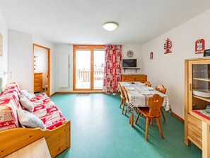 Um quarto acolhedor com uma cama, uma mesa de jantar com cadeiras, uma televisão e um armário.