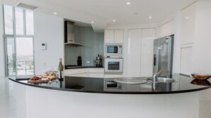 A modern kitchen with a central island, built-in microwave, oven, and stainless steel refrigerator.