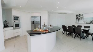 A modern kitchen with built-in appliances, a dining area with a curved island, and a large window with a view.