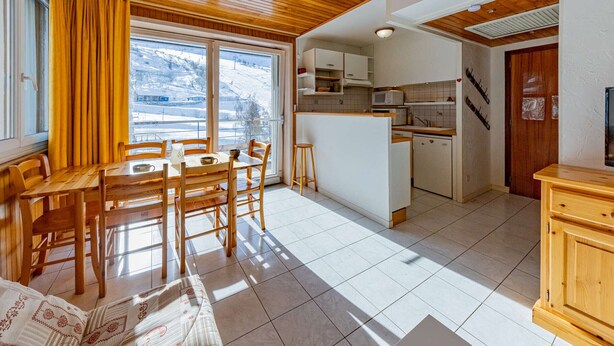 A cozy kitchen with wooden cabinets, a central island, and a dining area with a table and chairs.