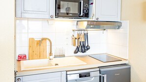 A compact kitchen with a microwave, oven, and dishwasher. - Modern 2-bedroom apartment at the foot of the slopes (Saint-François-Longchamp)