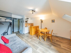 Um espaço compacto com cozinha compacta, área de refeições e sofá com almofadas vermelhas.