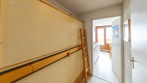 A hallway with a wooden wardrobe, a ladder, and a door leading to a balcony.