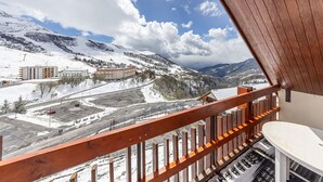 A balcony with a view of a snowy mountain landscape, including buildings and a road.