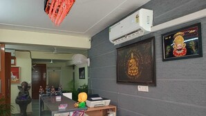 Ein Empfangsbereich mit Schreibtisch, Stühlen, Deckenventilator, Klimaanlage und einem gerahmten Buddha-Bild an der Wand.