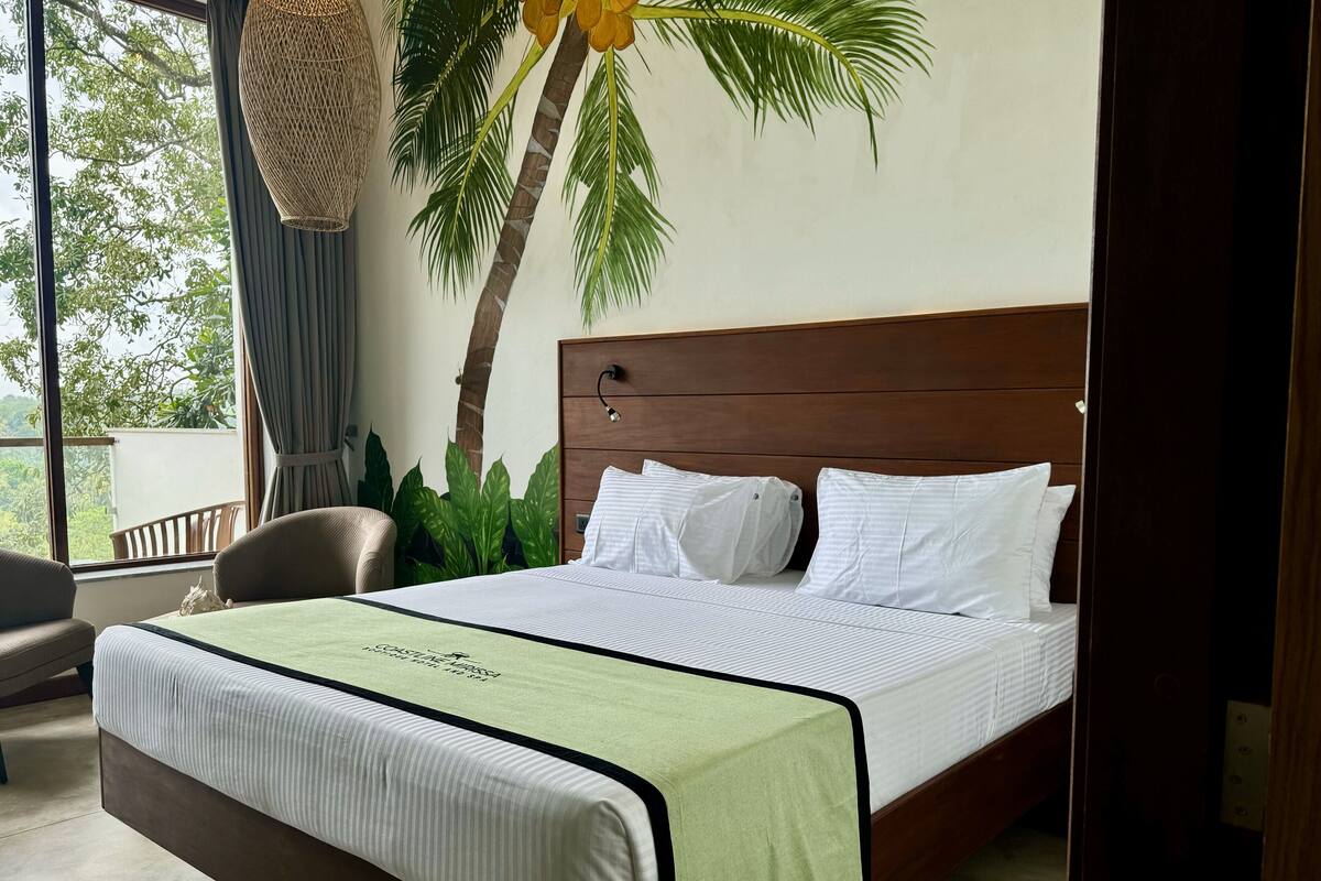 Una cama bien hecha con cubrecama verde y blanca, cabecera de madera y almohadas blancas.