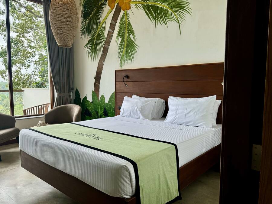 Una cama bien hecha con cubrecama verde y blanca, cabecera de madera y almohadas blancas.
