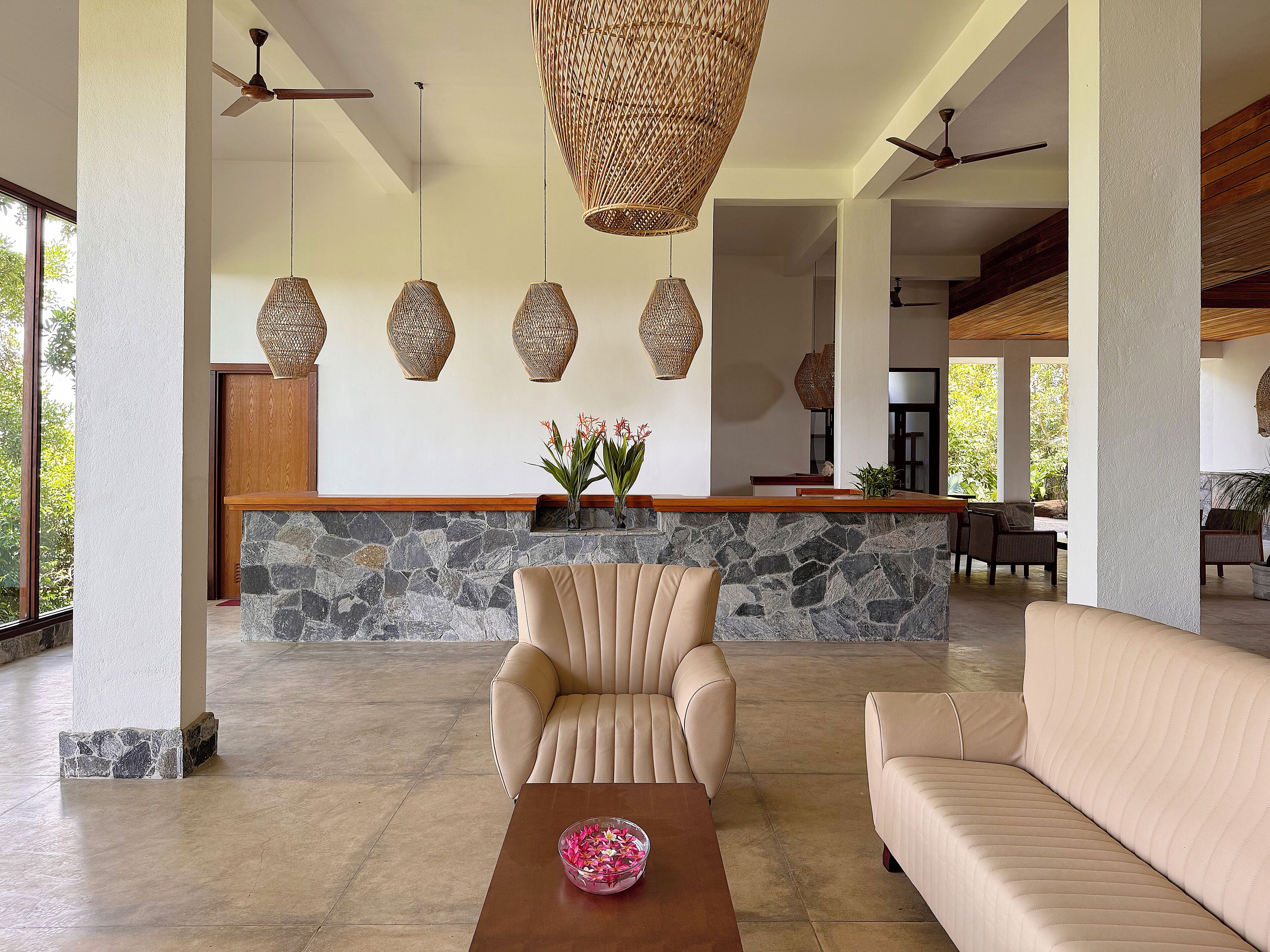 A spacious lobby with a stone wall, a reception desk, and a seating area with a sofa and armchair.