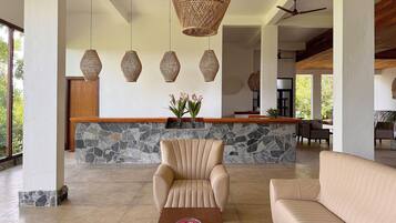 A spacious lobby with a stone wall, a reception desk, and a seating area with a sofa and armchair.