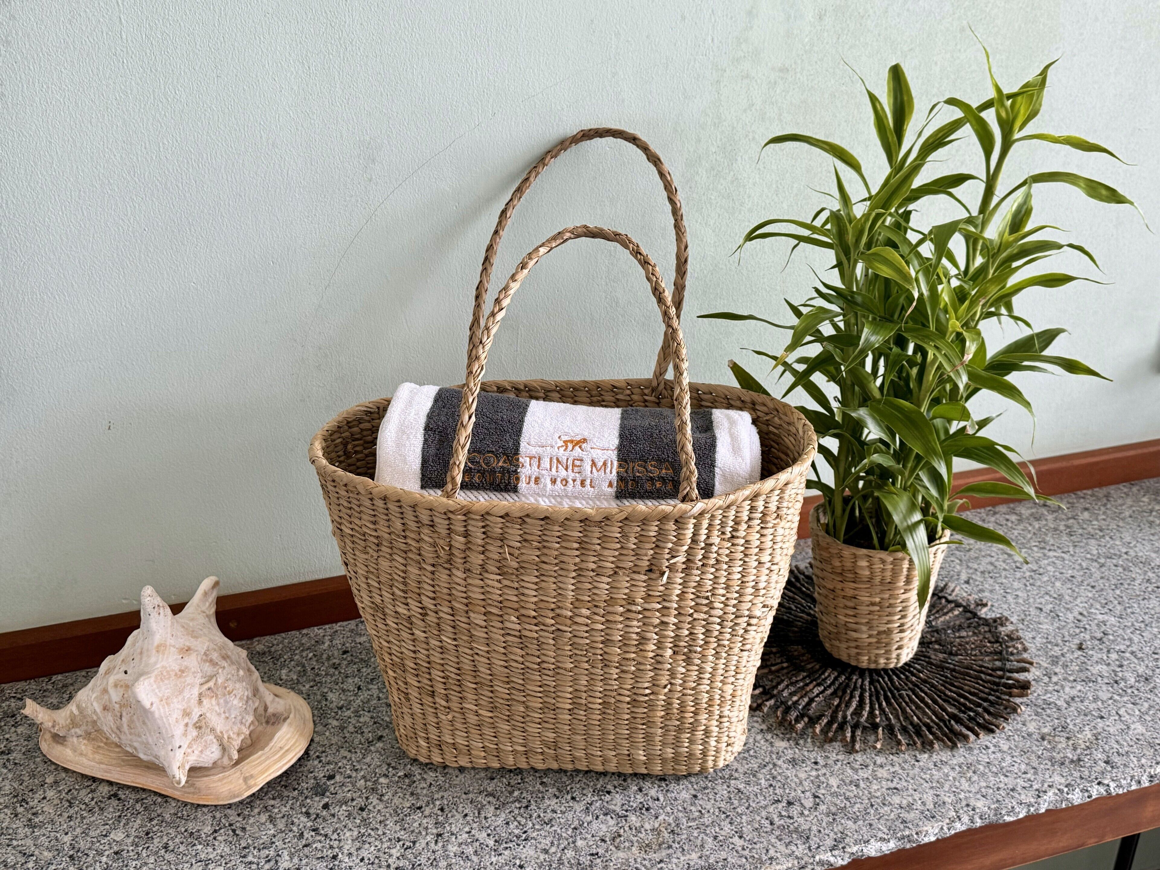 A wicker basket with a striped towel, a potted plant, and a seashell on a granite countertop.