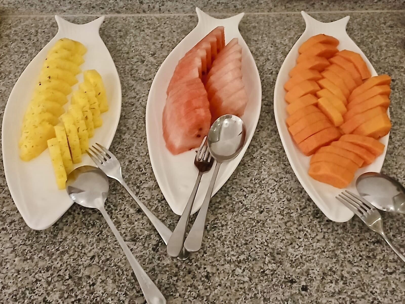 Três pratos brancos com comida sobre uma bancada de granito.