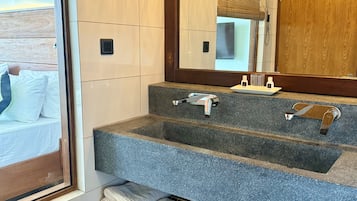 Un bagno con un lavabo in granito, uno specchio e una finestra con persiane.